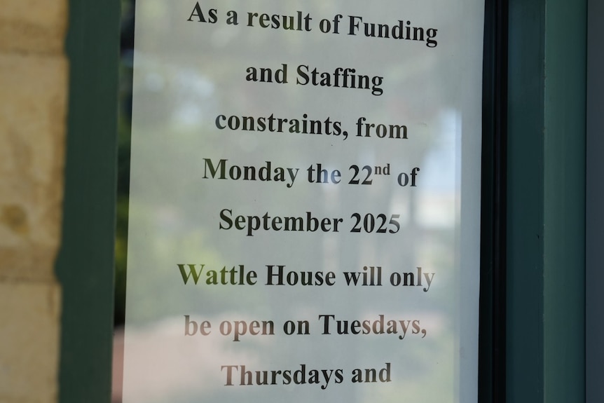A sign on a wall telling people that due to funding cuts a charity will only be opening three days a week.