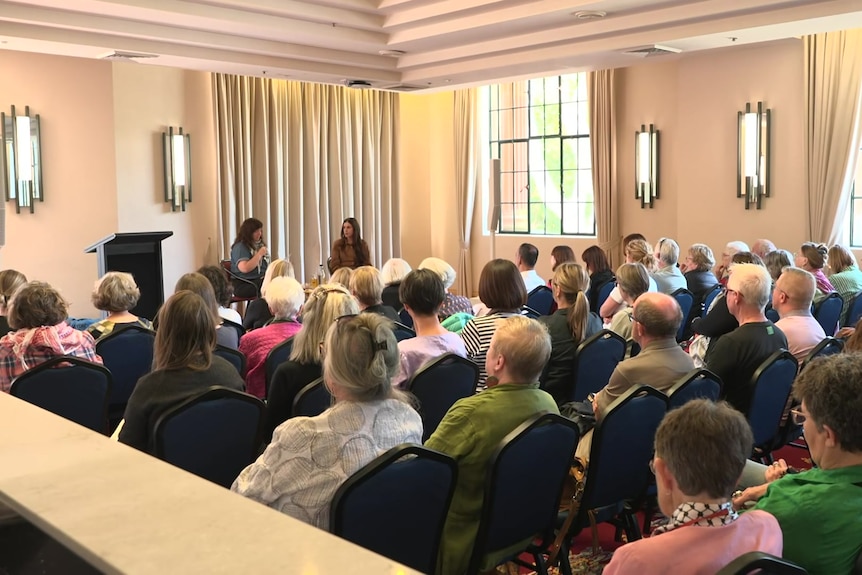 two women in conversation at a writers event, speaking in front of an audience