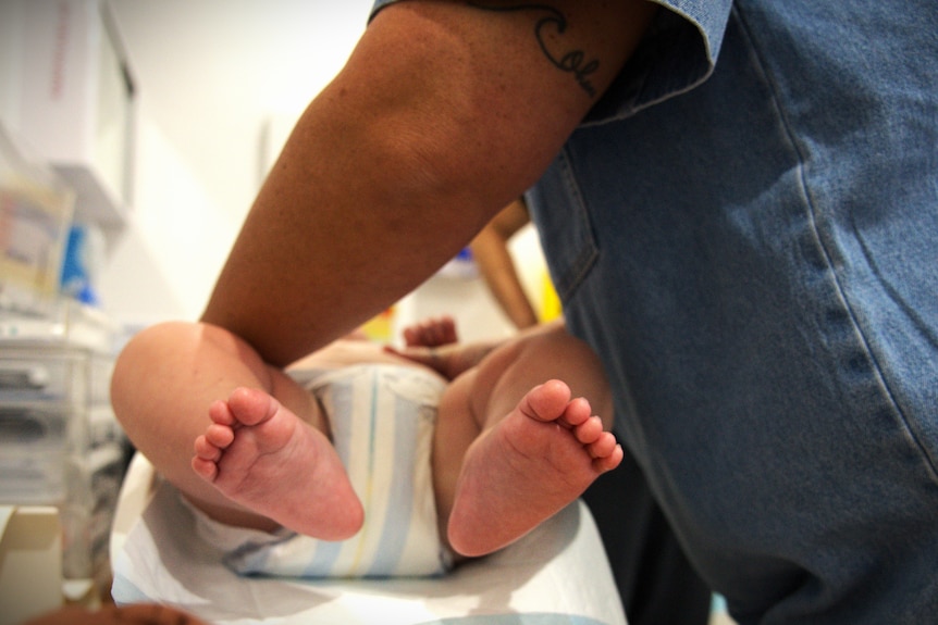 Baby feet and baby lying on a weighing machine. Can't see his face.