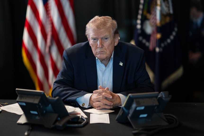 Donald Trump looking serious and sitting at a desk.