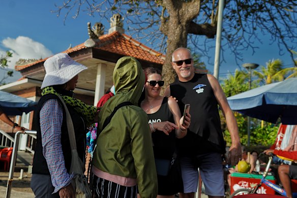 Australians David and Natalie Ritter at Kuta Beach recently with drink and trinket sellers – old friends of theirs – on a video call to the kids. 