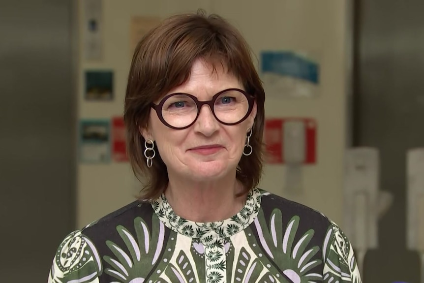 A woman with glasses looking towards the camera