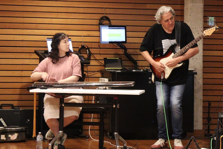 A woman and a man play instruments next to each other.