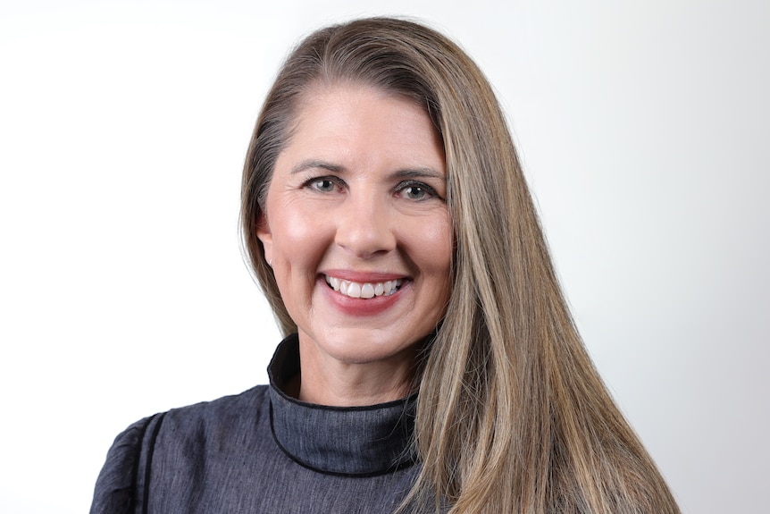 Jayde Richmond headshot, with brown hair, and a black shirt, smiling.