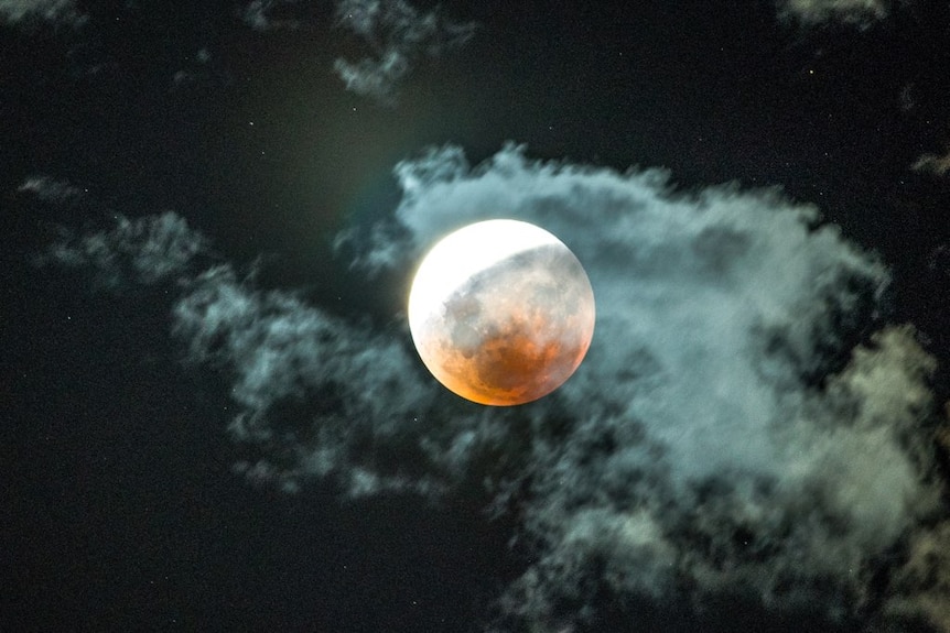 A red and white moon in a dark sky