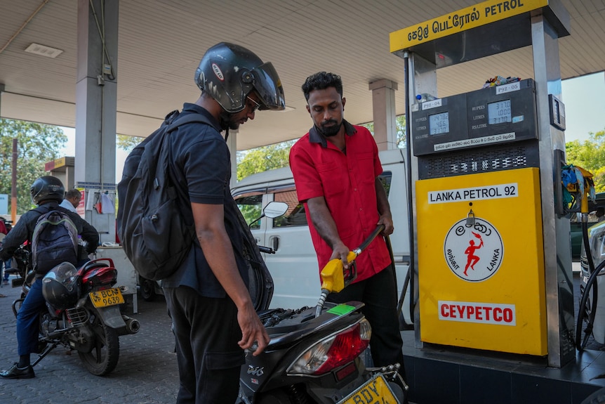 man fills up tank of motorbike.