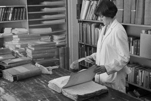 black and white photo of woman Vacuuming incoming records for cleaning and ridding of pests, 1969