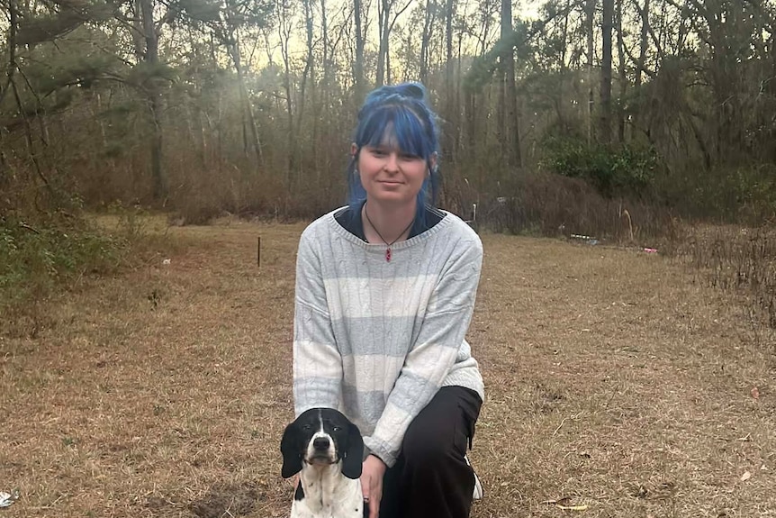 Kiley smiles at camera in the bush land in Florida with her dog