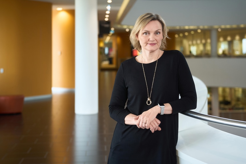 Medium close up of blonde woman wearing a black jumper smiling at the camera