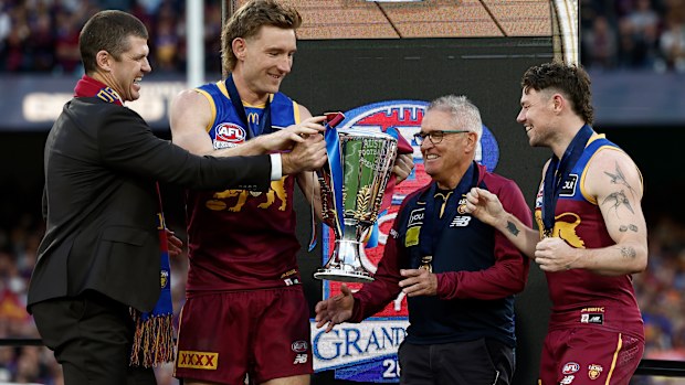 Jonathan Brown presents Harris Andrews of the Lions, Chris Fagan, Senior Coach of the Lions and Lachie Neale of the Lions with the Premiership Cup on the dais during the AFL Grand Final match between the Geelong Cats and the Brisbane Lions at the Melbourne Cricket Ground on September 27, 2025 in Melbourne, Australia. (Photo by Michael Willson/AFL Photos via Getty Images)