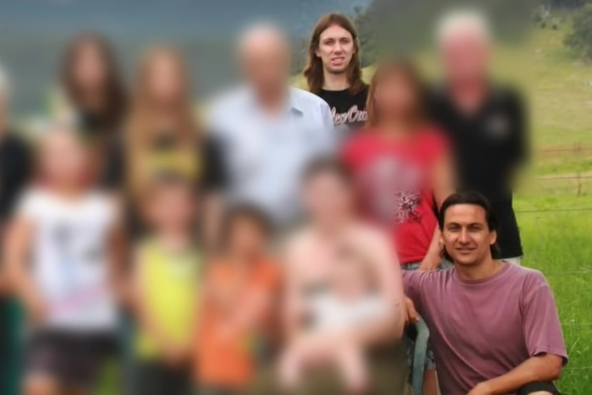 A photo of a large group of people. All of their faces are blurred apart from two men.