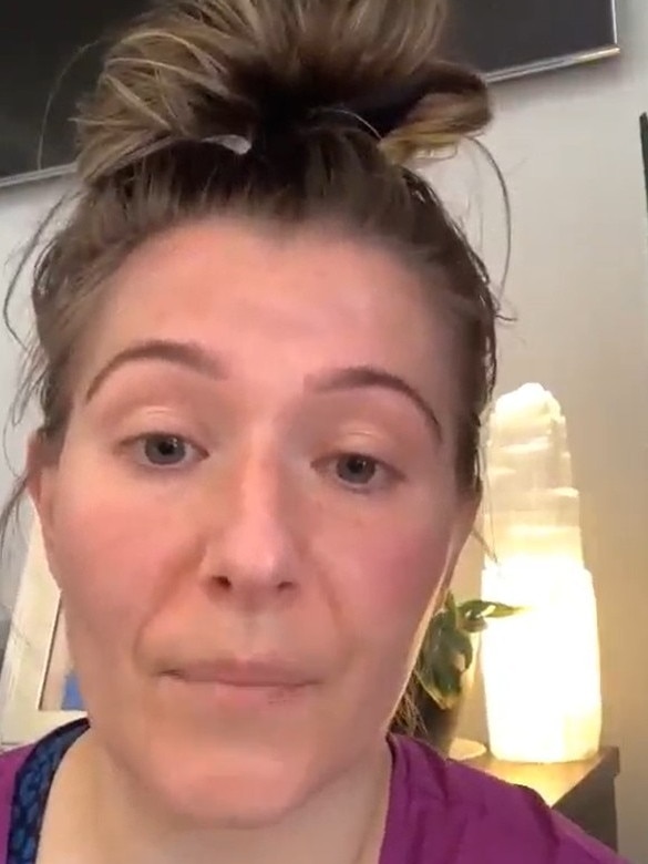 A woman in a pink shirt with hair pulled into a bun on top of her head stares at the camera.