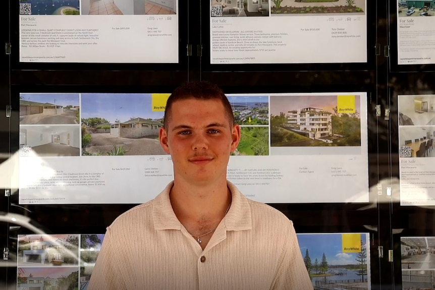 A young man stands in front of rental property ads.