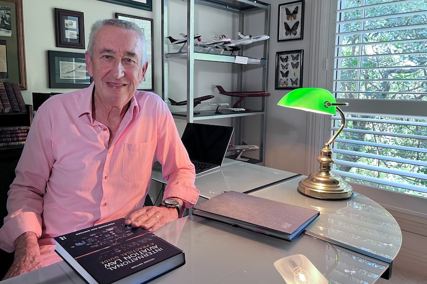 A professor sitting in his office with model airplanes on shelves behind him.