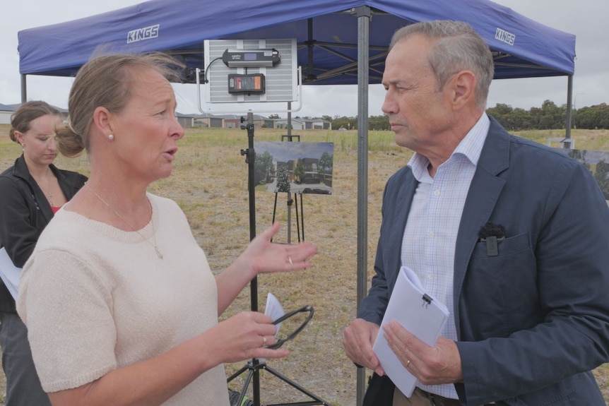 Woman in white top on left talking to Roger Cook on right