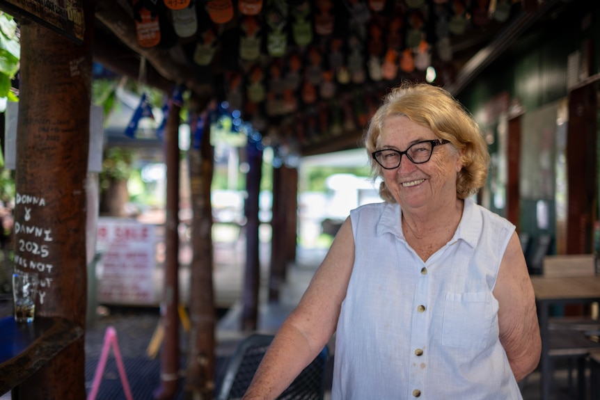 A woman in a white shirt and glasses smiling