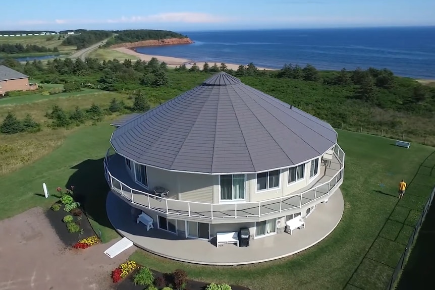 Areal shot of a round house on a green waterfront property 