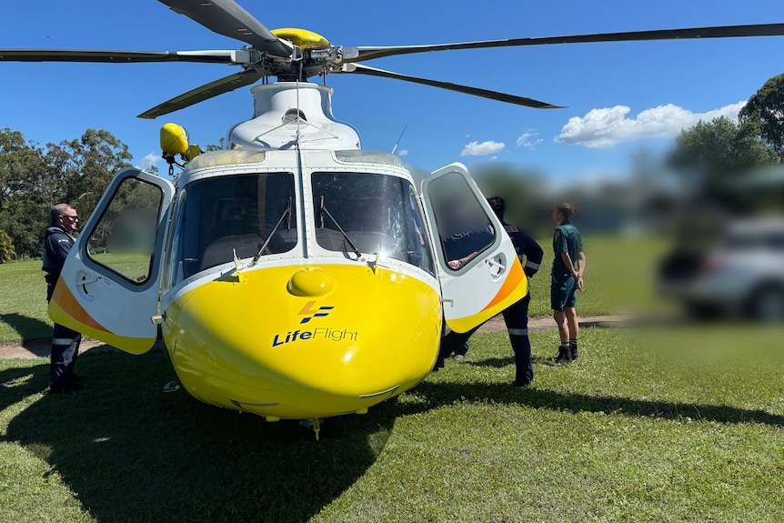 A rescue helicopter on a green field with people beside it an a patient blurred out