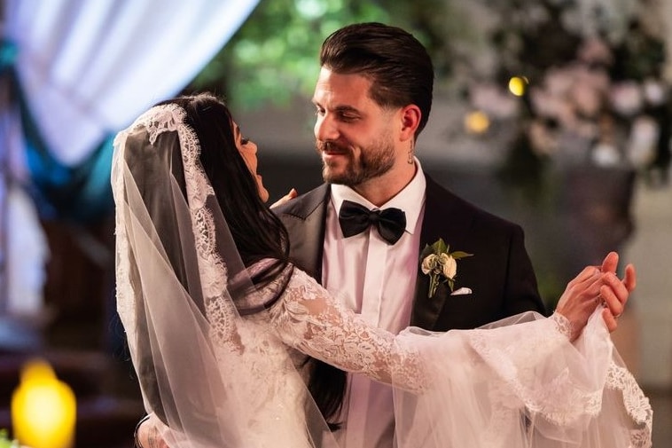 A bride and groom dancing in a candlelit room.