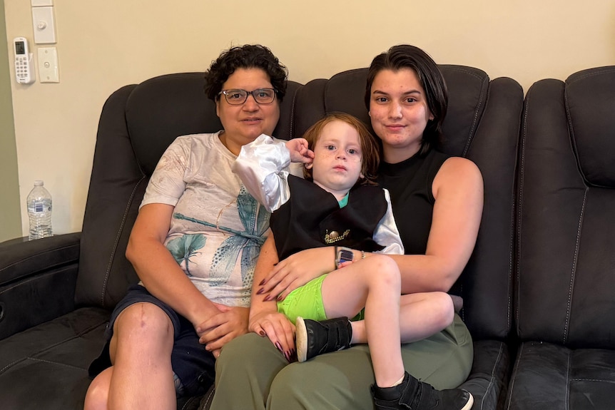 Belinda Menzies (left) with Maddie Menzies, 24, and Elliot sit on a couch.