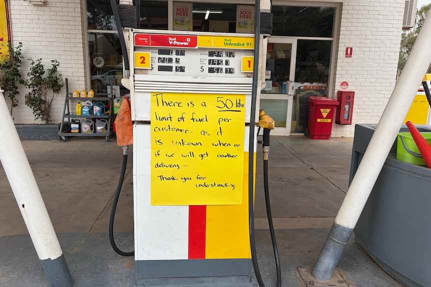 A yellow and white petrol bowser with a yellow sign alerting customers to a 50 litre supply restriction.