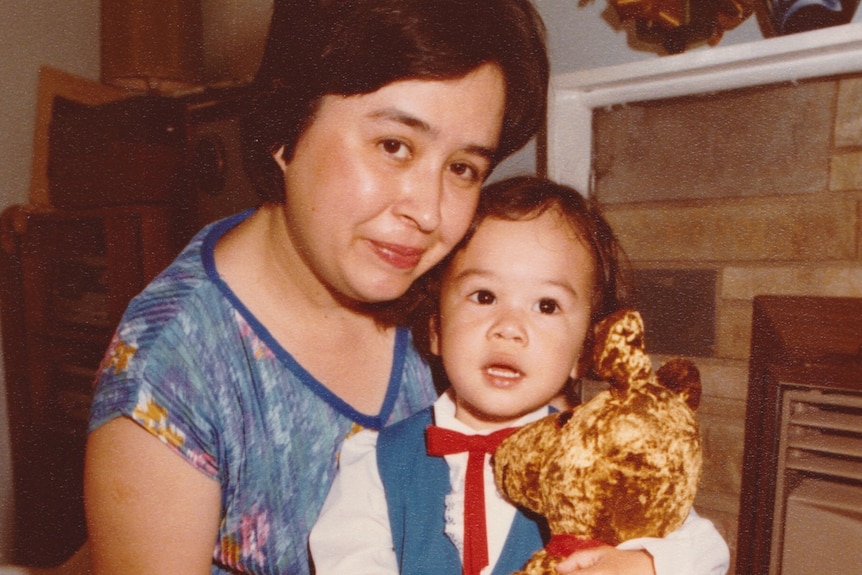 a woman and young boy holding teddy look at the camera