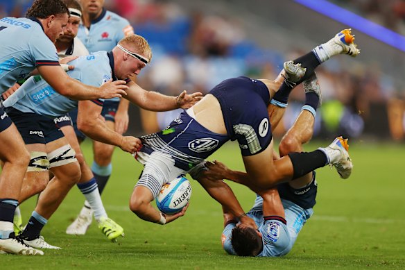 Caleb Clarke is tackled by the Waratahs.