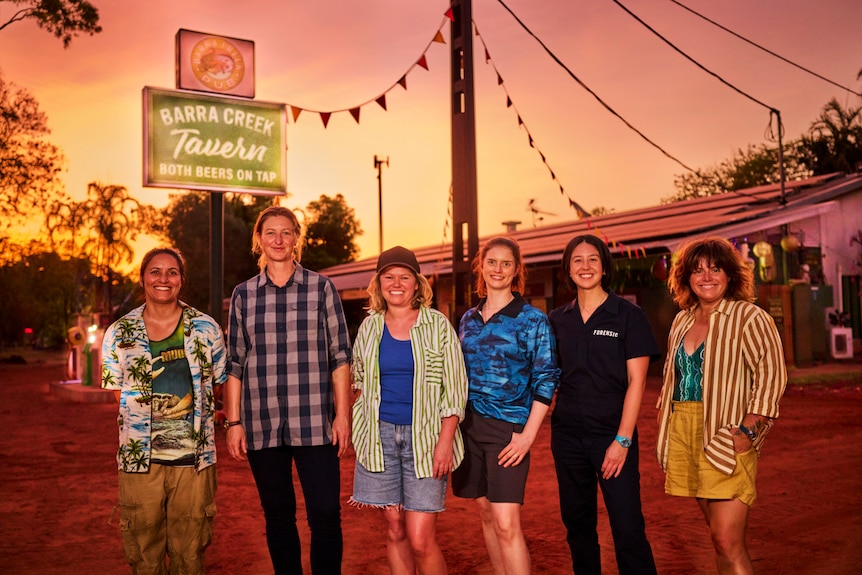 The cast of Deadloch, and writers Kate McLennan and McCartney, centre, smiling outside a country pub in the NT.