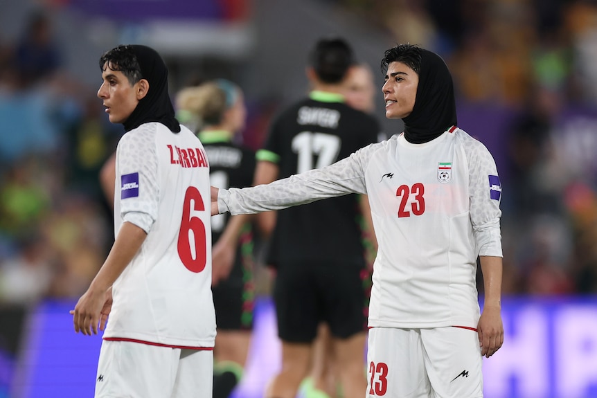 An Iranian women's team player puts her hand on a teammate's shoulder after a moment in a Women's Asian Cup match.