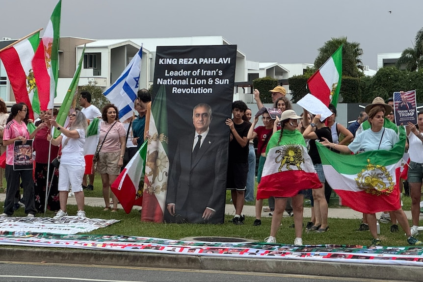 Iranian Australian demonstrators hold up an image of Reza Pahlavi at the Women's Asian Cup.