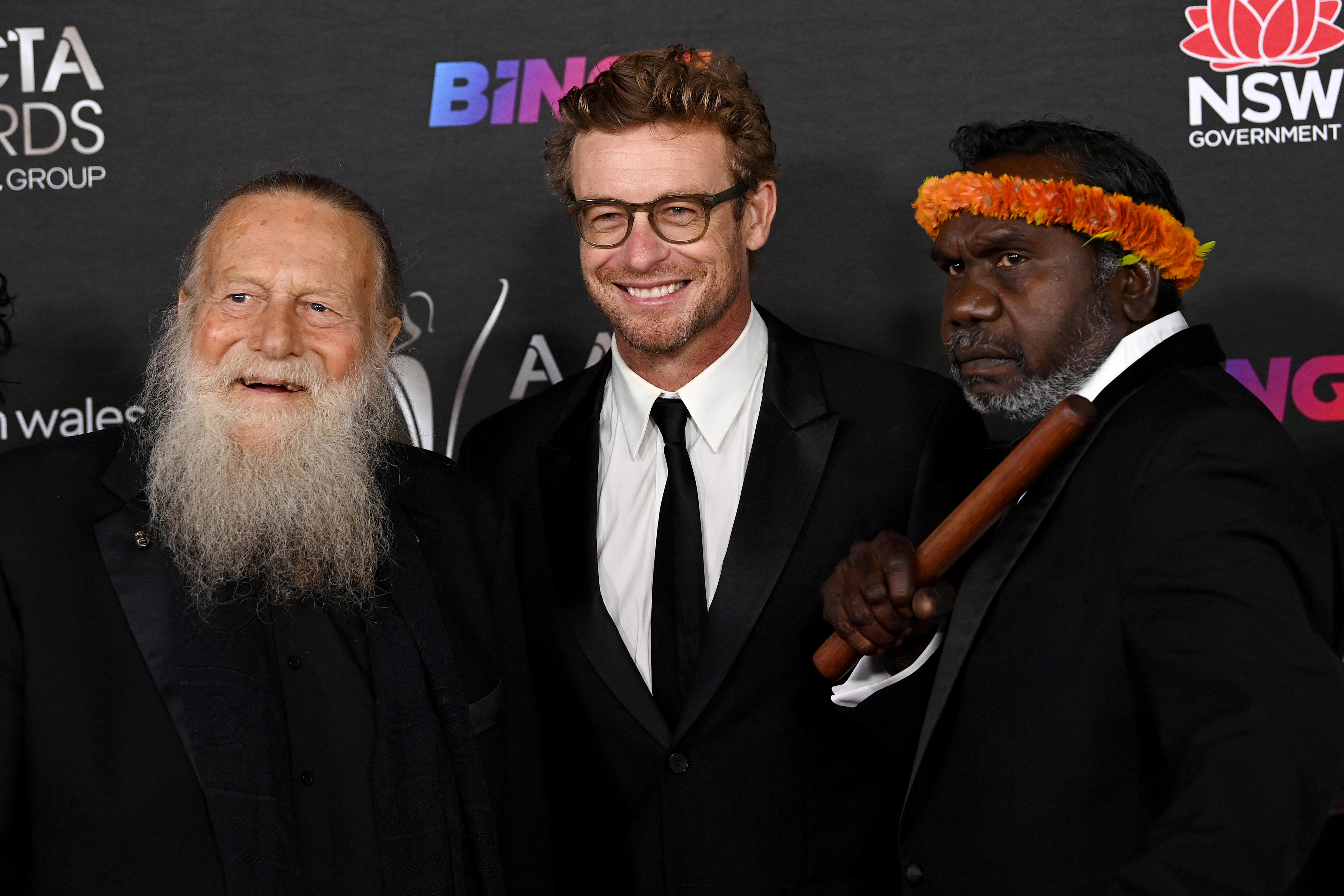 Jack Thompson, an older man with a long white beard with Simon Baker and Witiyana Marika who wears an orange headdress.