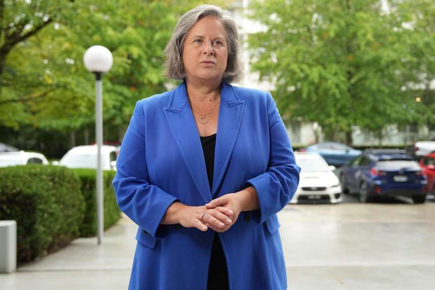 A woman dresed in blue standing in a street. 