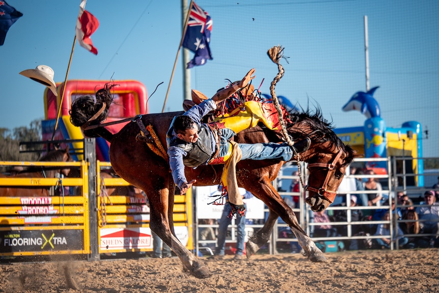 A man falls off a bucking bronco