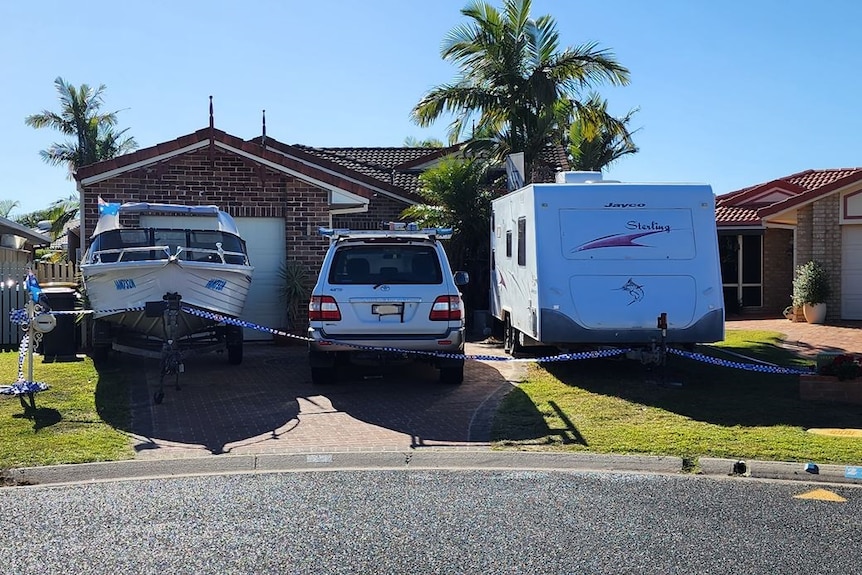 Police cars and crime scene investigators at Yamba house. A boat and caravan are parked in the drive of the house