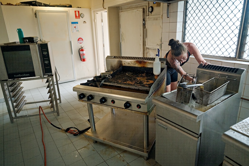 A woman cleans a kitchen in the aftermath of a flood.