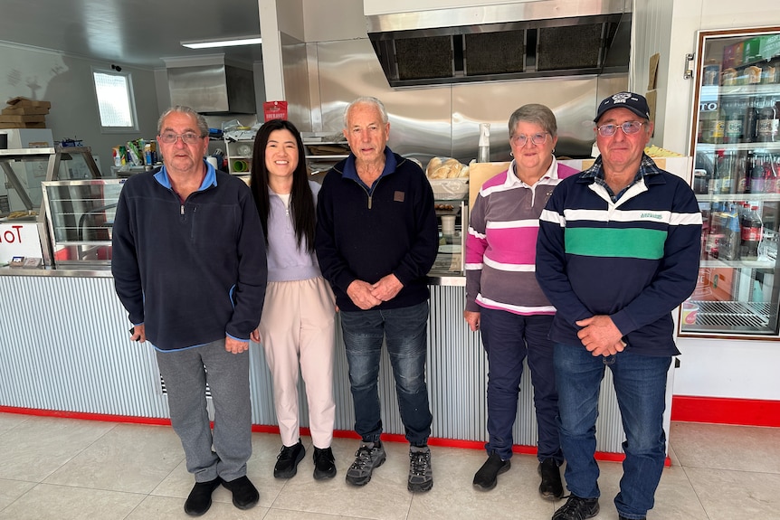 Annie and four elderly people pose inside a take away shop.