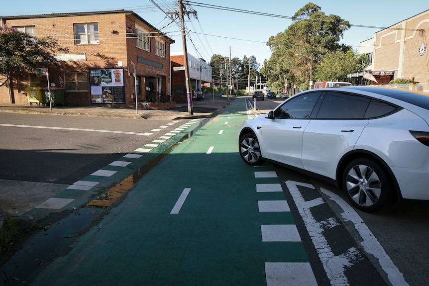 a car turns left across a green-painted cycleway