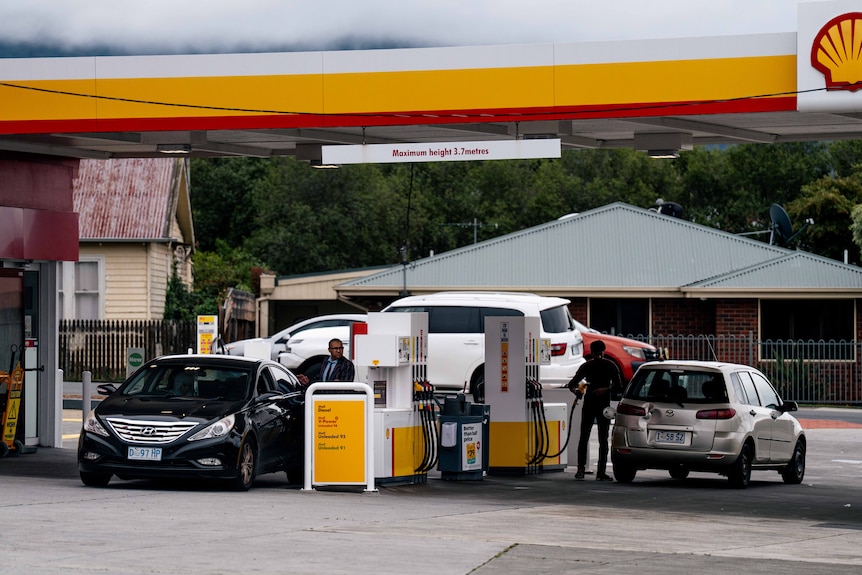 Two men filling up their cars with petrol at a Shell service station in Hobart.