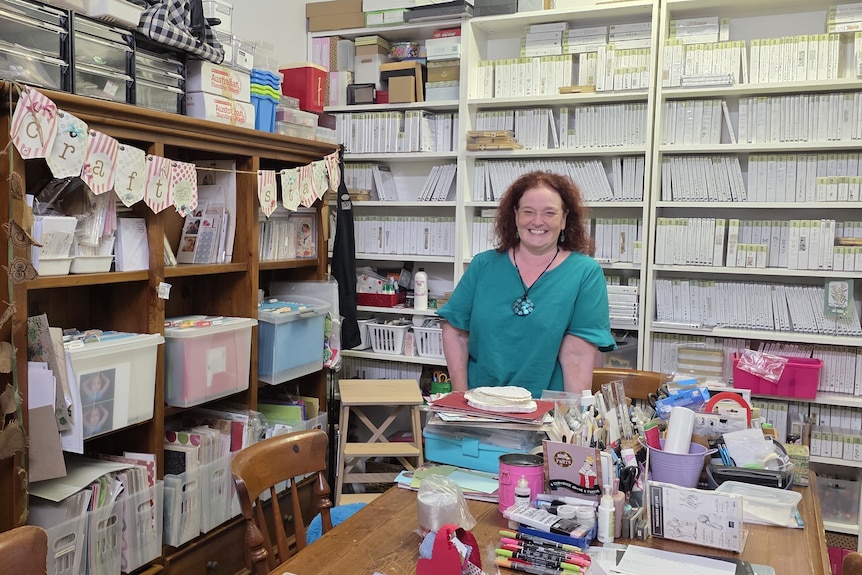 Lady standing in a room full of shelves filled with tubs and art supplies.