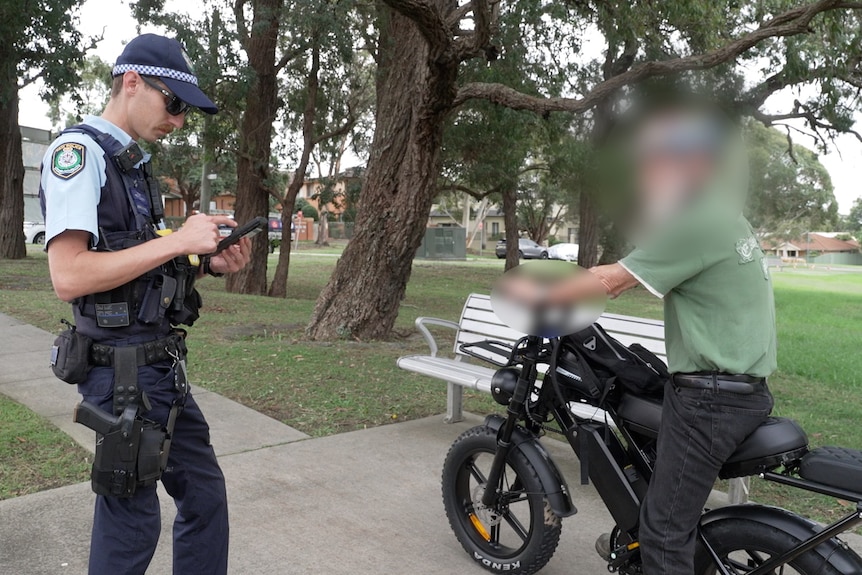 a police officer issues a fine to an illegal e-bike rider