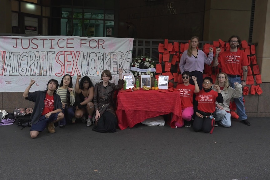 A group of people crouch with fists raised in front of a sign that reads "justice for Asian migrant sex workers".