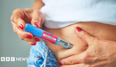 Woman with red nails, administering a weight-loss jab into her stomach