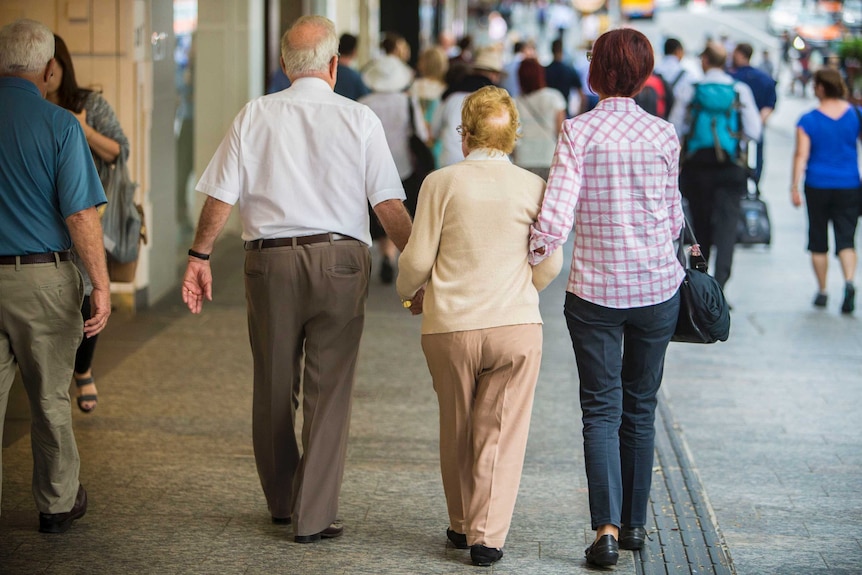 An elderly couple down a mall with the help of a younger woman.