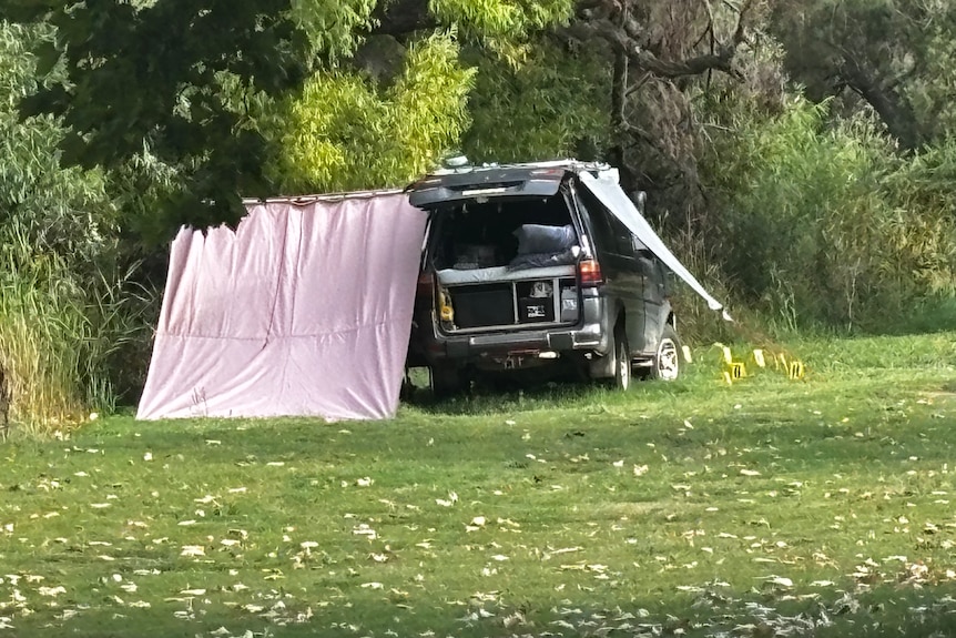 A car with a tent set up next to it on a grassy area.