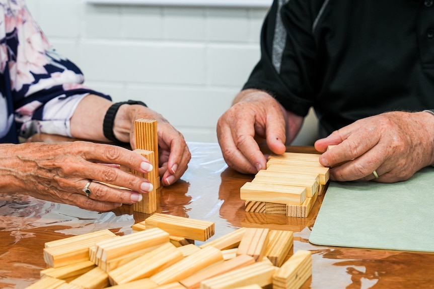 A man and a woman doing a Jenga at a table.