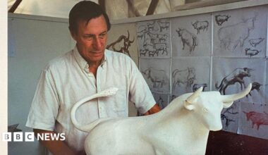 Sculptor Laurence Broderick standing behind the maquette the Bull with previous sketches behind him