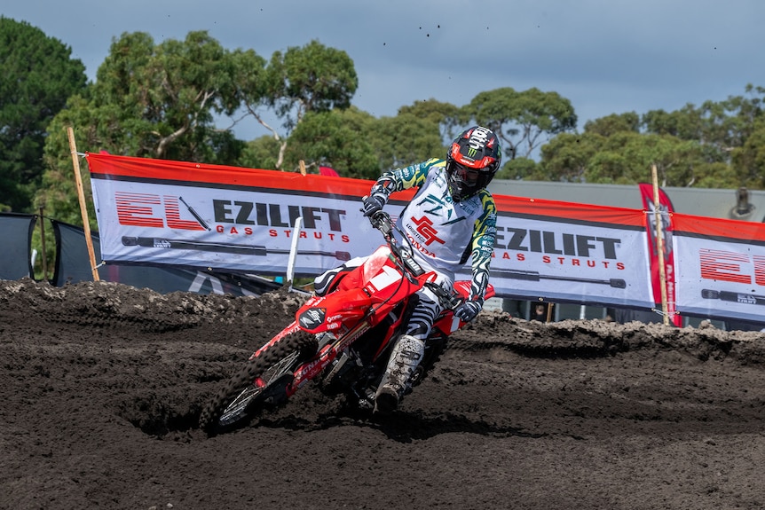A female motocross rider with their leg out going around corner.
