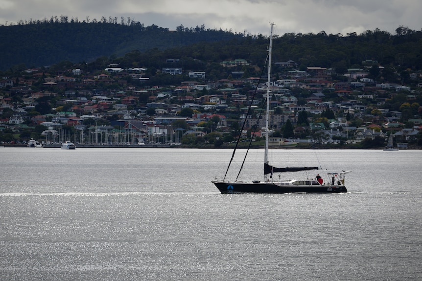 A yacht with its sails down, on calm waters.
