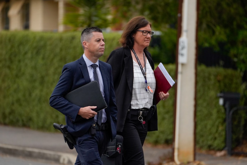 Two people walking on street with folders in their hands