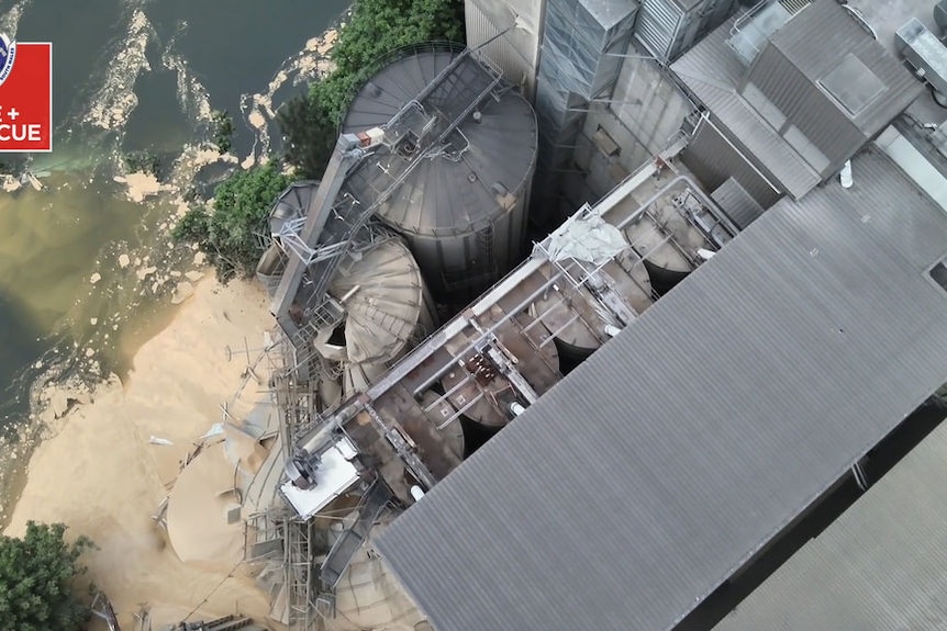An overhead shot of a collapsed silo with grain flowing into a river.